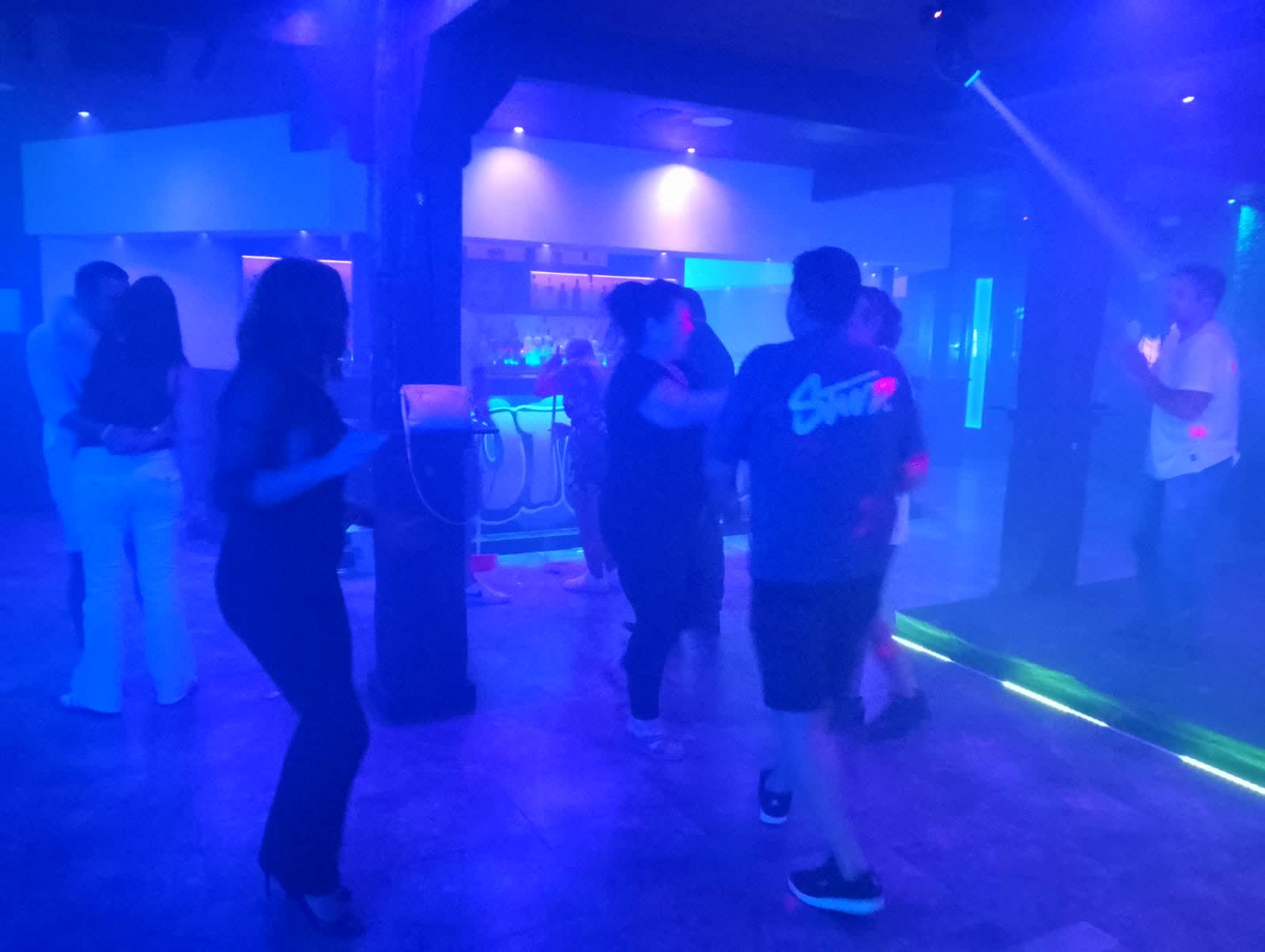 Gente bailando en la pista entre luces azules y moradas